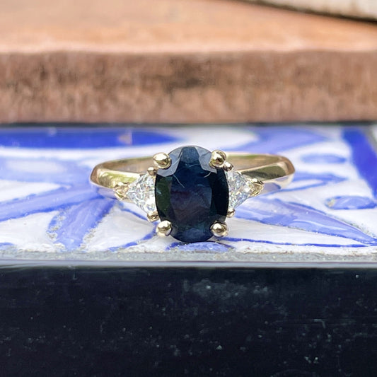 14KT Yellow Gold Oval .95 CT Blue Sapphire + Trillion Diamond Accent Ring